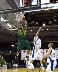 Chad in a green basketball jersey (#24) jumping in the air to get the ball into the basket.